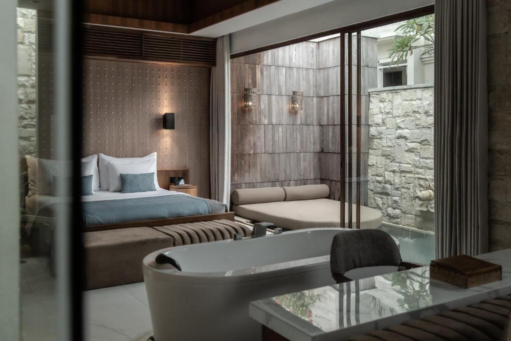 a bedroom with a bed and a tub in a room at La Vie Villa Seminyak by Ini Vie Hospitality in Seminyak