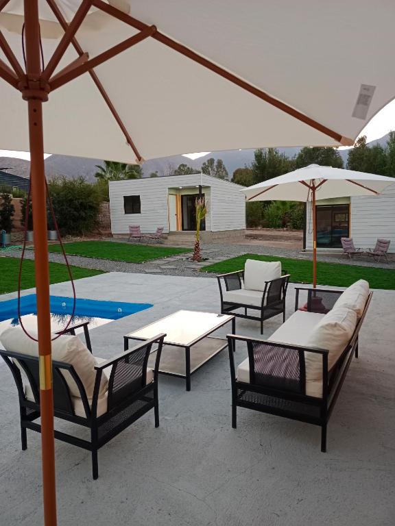 a patio with chairs and tables and an umbrella at Cabañas Lodge el Mauco in Curacaví