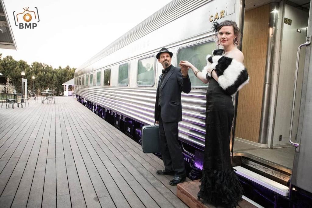 a man and a woman standing next to a train at The Historic Railway Barracks in Goulburn