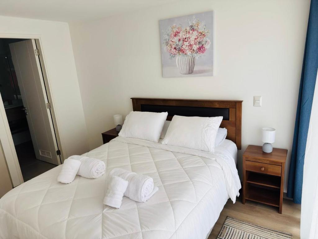 a bedroom with a large white bed with towels on it at Departamento Temuco Centro in Temuco