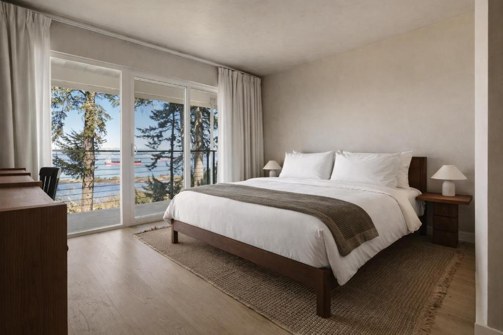 a bedroom with a large bed and a large window at The Herondale Hotel in Astoria, Oregon