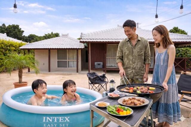 a man and a woman and two children in a swimming pool at Fukugi Beach Villa Okinawa in Nakijin