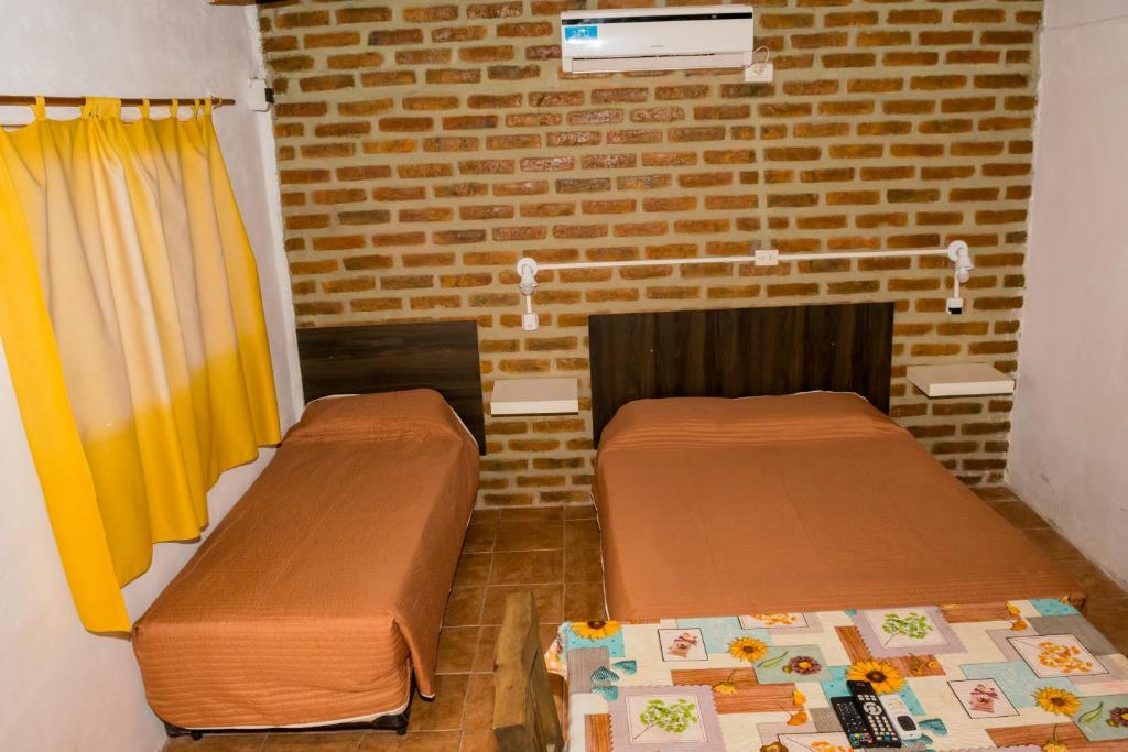 a room with two beds and a brick wall at Cabañas de Campo in Villa Unión