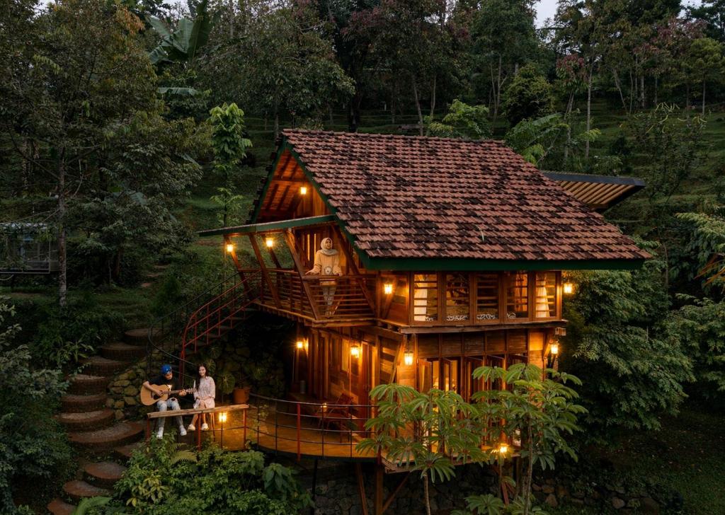 a family standing in front of a tree house at Kebun Hanoman Private Villa in Pablengan