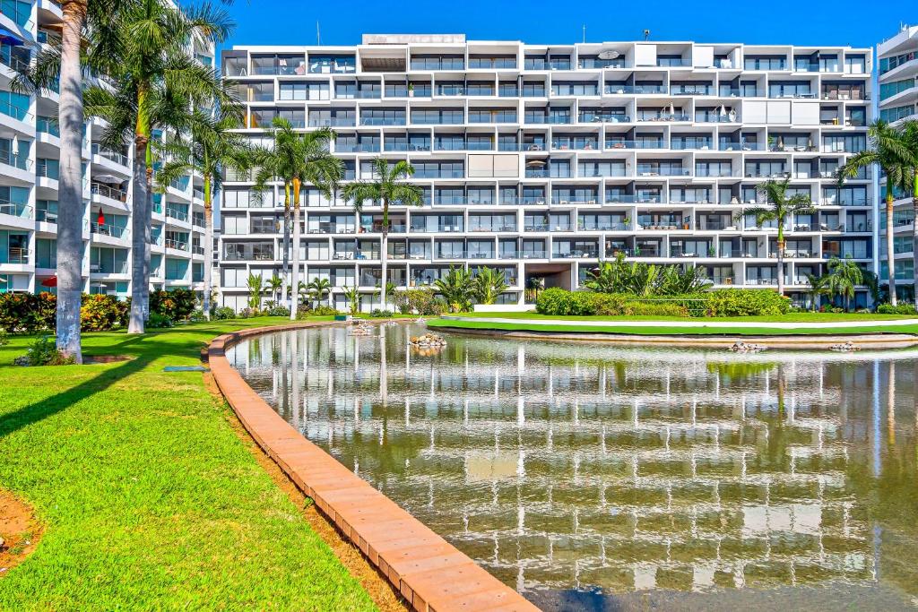 a large building with a pond in front of a building at Oceanfront condo with a full kitchen, pool, & beach access in Nuevo Vallarta