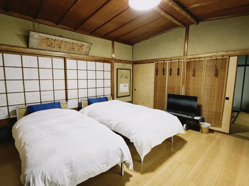 two white beds in a room with a tv at 直島古民家一棟貸し笑くんNaoshima 'Shoukun' Entire house in Naoshima