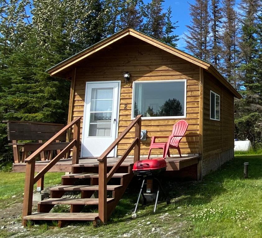 a cabin with two pink chairs sitting on a deck at Blue Moose Cabin at Moose Tracks Lodging in Kenai