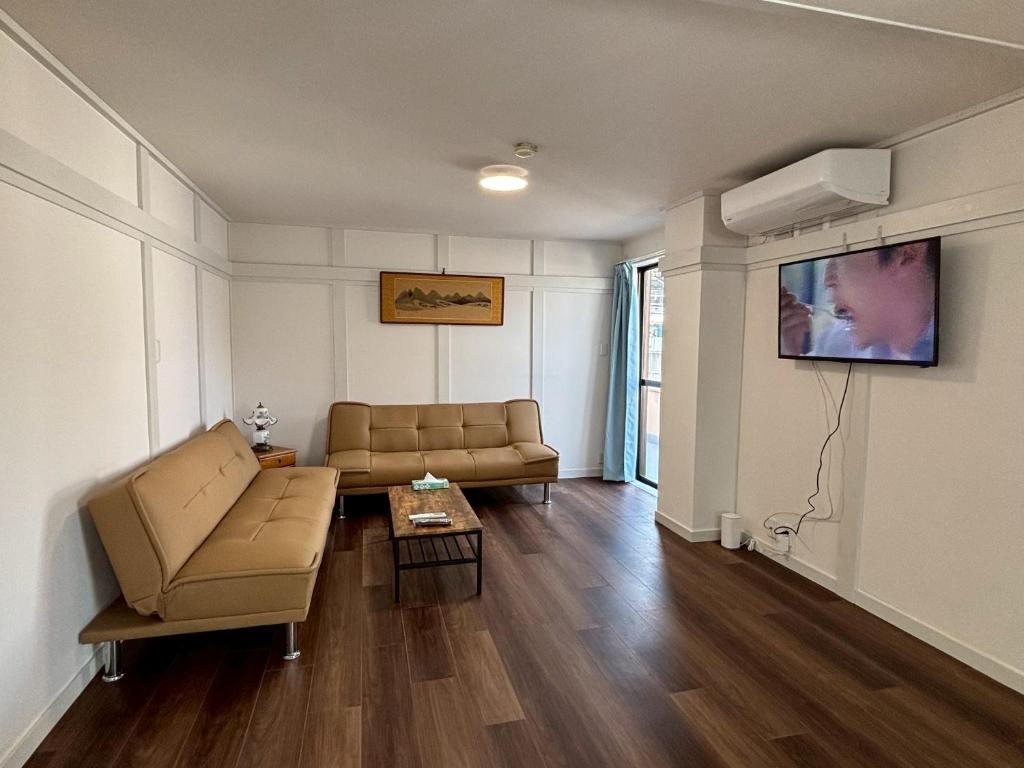 a living room with a couch and a tv at 京阪楽宿 in Kadoma