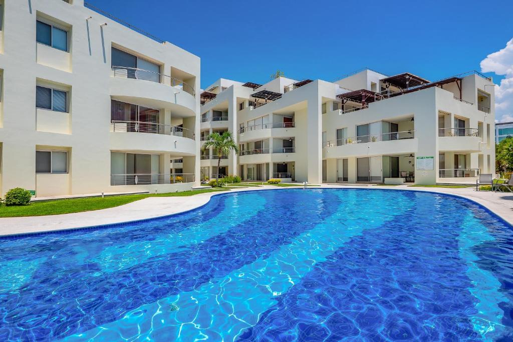 a large swimming pool in front of a building at Stylish condo with covered balcony, pool & pool tables in Nuevo Vallarta