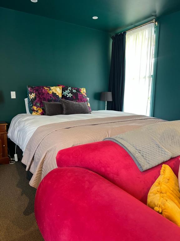 a bedroom with a large bed and a red couch at Pinot Villas in Martinborough