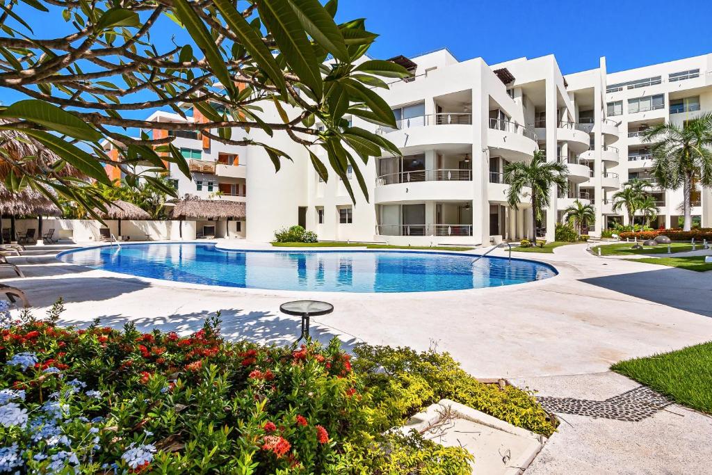 a large apartment building with a large swimming pool at Ocean-view condo with resort pool & sundeck in Nuevo Vallarta