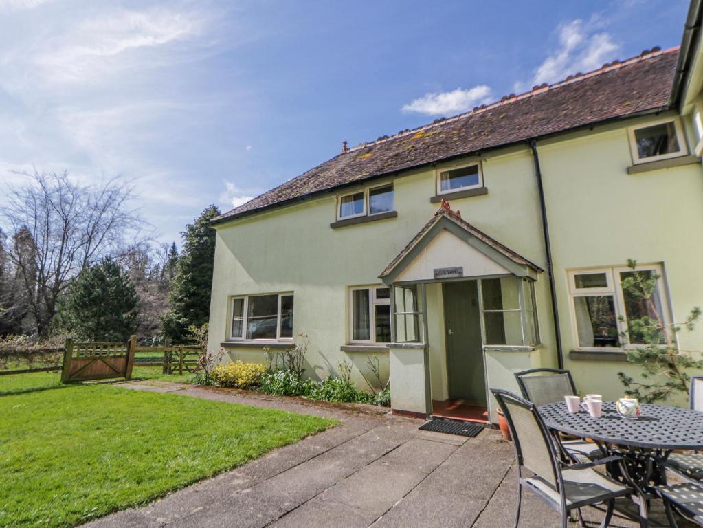 a house with a table and chairs in the yard at Gardener's Cottage in Llandrindod Wells