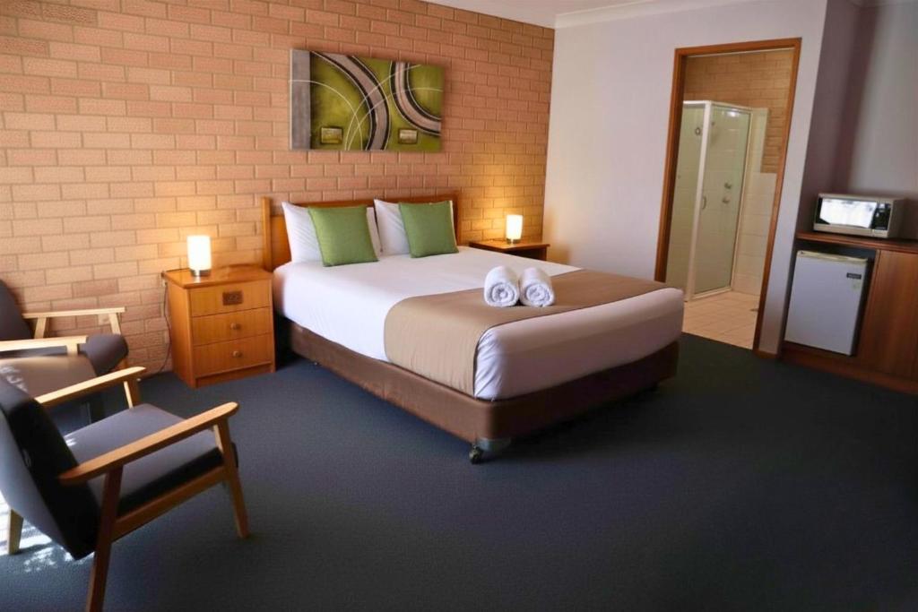 a bedroom with a large bed with two towels on it at Golden Chain Aalana Motor Inn in Cowra