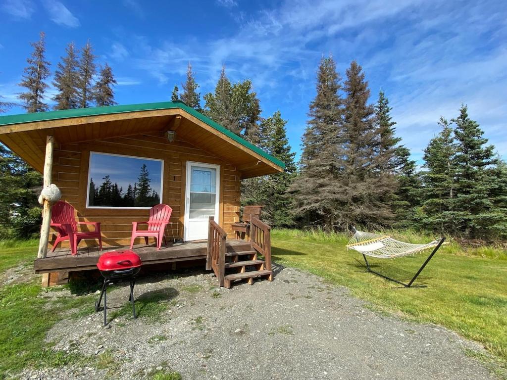 a log cabin with two chairs and a hammock at Rustic Moose Cabin at Moose Tracks Lodging in Kenai