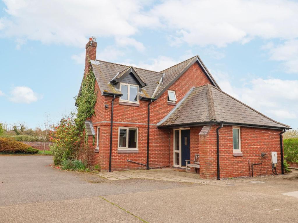 a red brick house with a gray roof at Manor Wood in Coddington