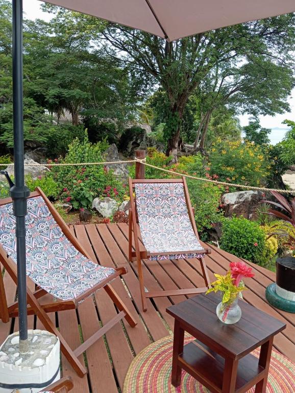 two chairs and a table on a deck with an umbrella at VILLA Paradisakely in Nosy Be