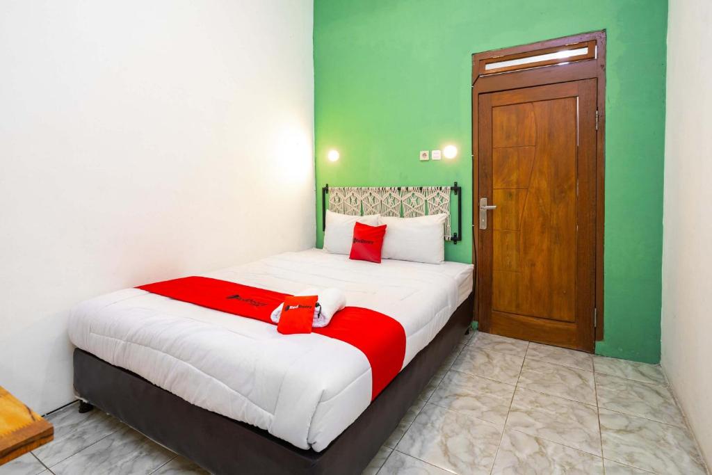 a bedroom with a large bed with a red blanket at RedDoorz near Exit Toll Tanah Baru Bogor in Bogor