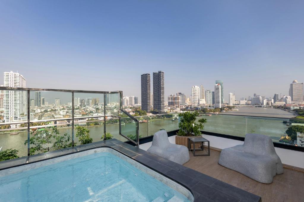 A rooftop pool terrace with river and city views, outdoor loungers and sculptural seating.