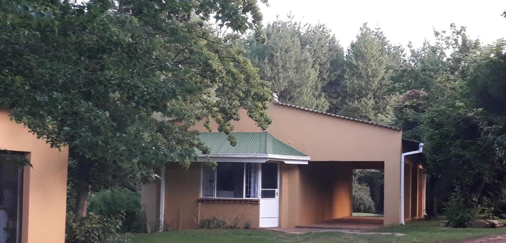 een huis met een groen dak en een boom bij Sanfern Downs Cottage in Haenertsburg