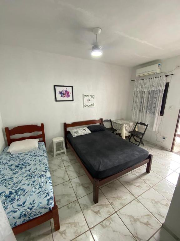 a bedroom with two beds and a table in it at Dina Suítes Flat's Caiçara in São Sebastião