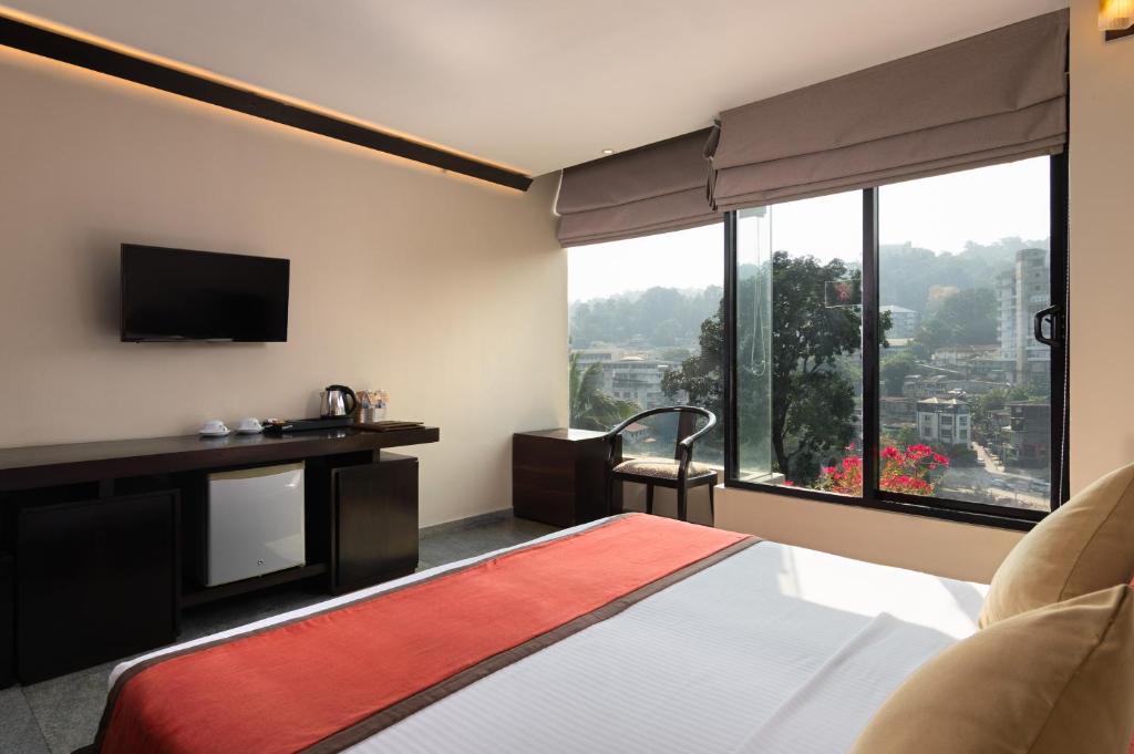 a hotel room with a bed and a large window at Oak Ray City Hotel in Kandy
