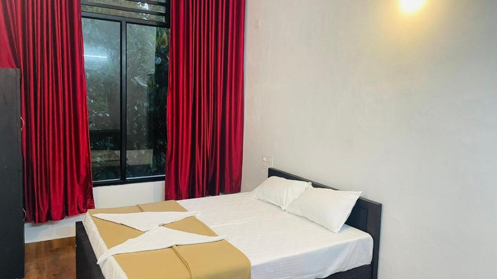 a bed in a room with red curtains and a window at EK Residency in Anaviratty