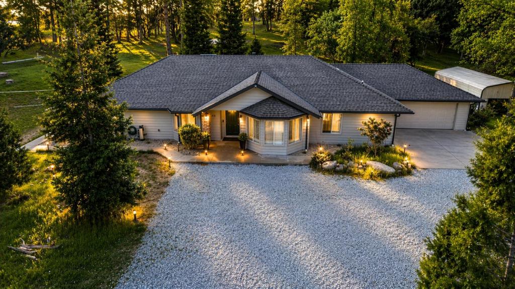 a house with lights in front of a driveway at Spacious Ranch Retreat Near Yosemite & Bass Lake with Hot Tub & Game Room in Oakhurst