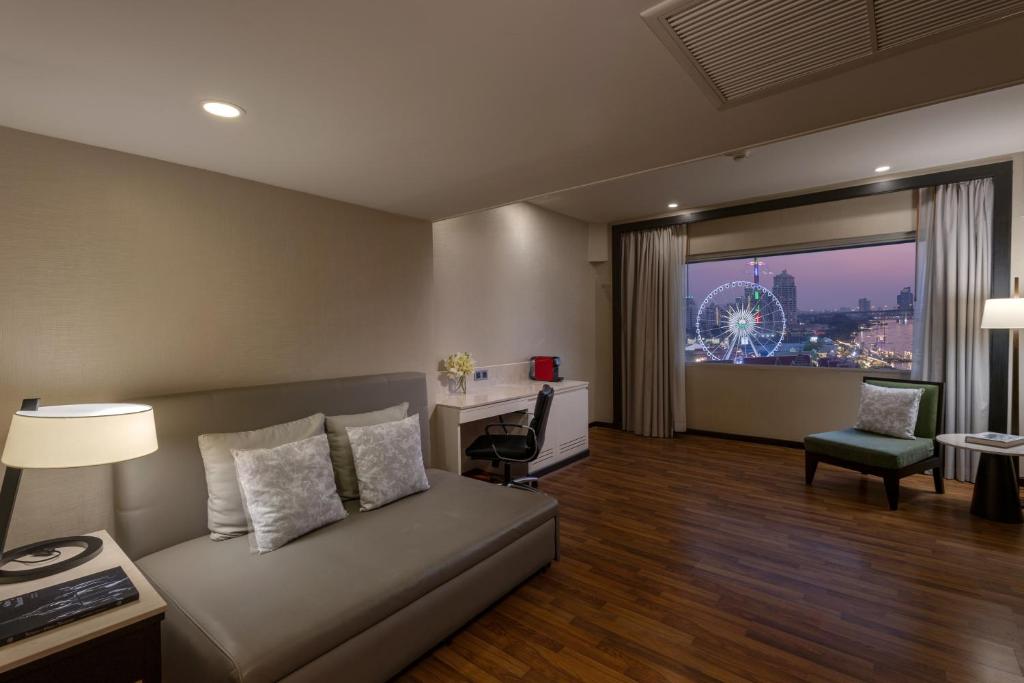 A softly lit living room with a sofa, work desk and illuminated evening riverfront view.