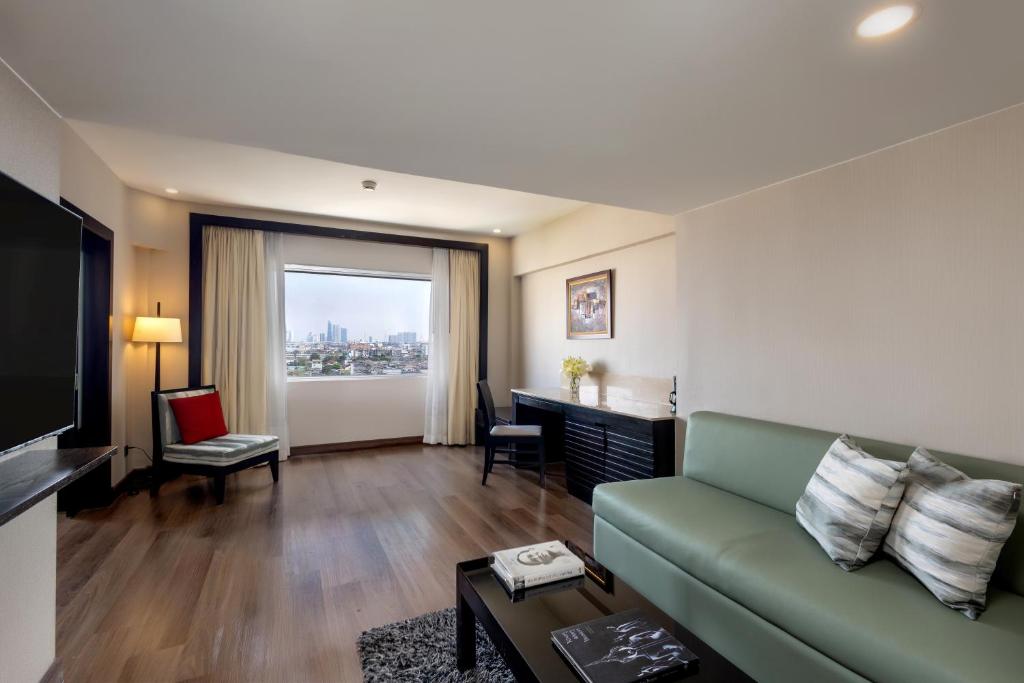 A spacious living room with a green sofa, work desk and broad city view.