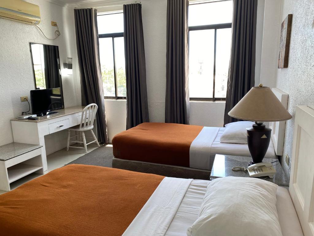 a hotel room with two beds and a desk at Stonestown Suites in Balulang