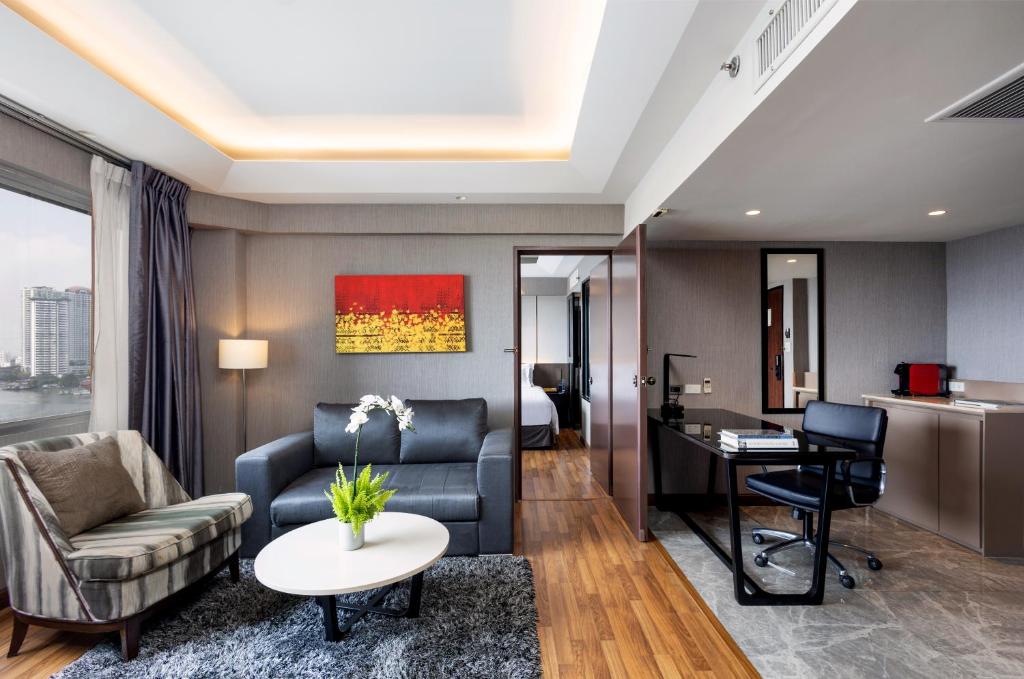 A suite-style living area with sofas, a desk and a compact kitchenette or refreshment counter.
