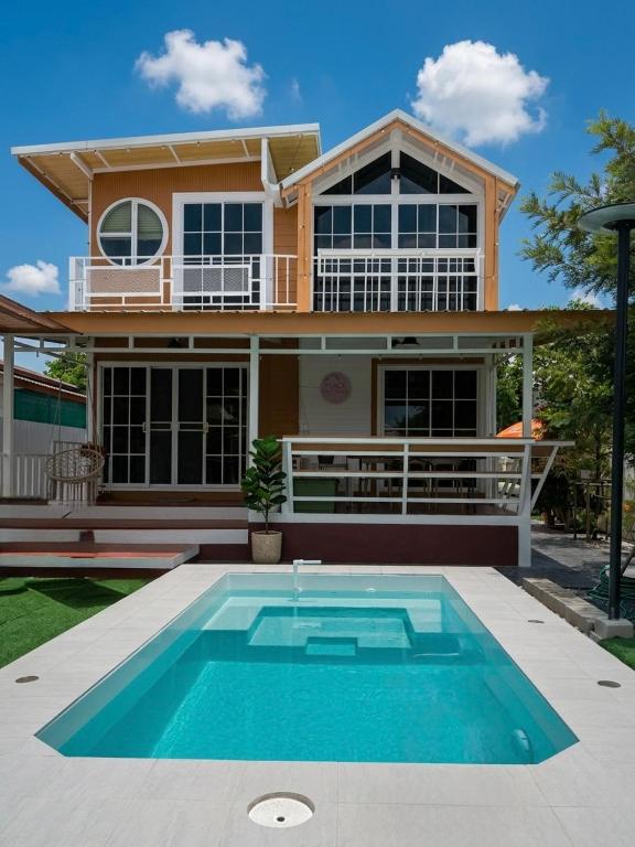 a house with a swimming pool in front of a house at Peace poolvilla sattahip พีซ พลูวิลล่า สัตหีบ in Ban Tao Than