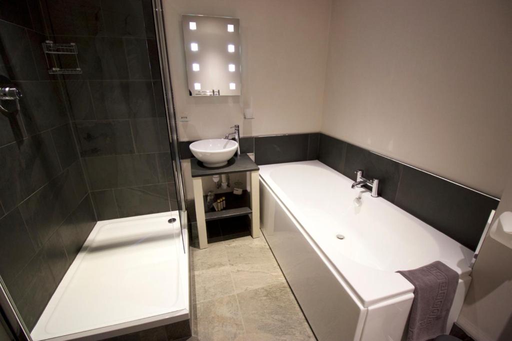 a bathroom with a tub and a sink and a shower at The Woolacombe Bay Hotel in Woolacombe