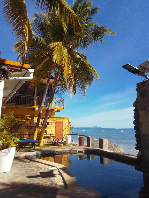 a house with a palm tree and a swimming pool at Le Lagon Bleu in Antsatrakolo