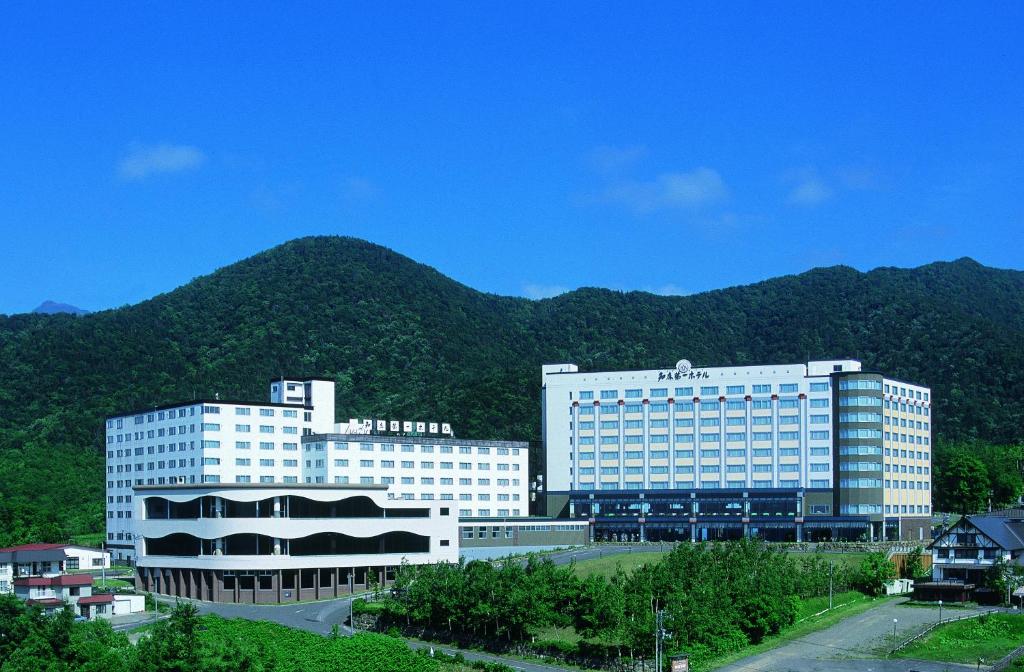 two white buildings in front of a mountain at Shiretoko Daiichi Hotel in Shari