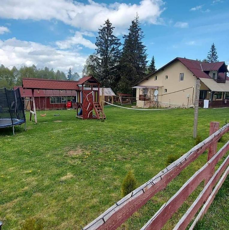 a yard with a fence and a playground at Cabana Duma la munte cu ciubar in Dealu Negru