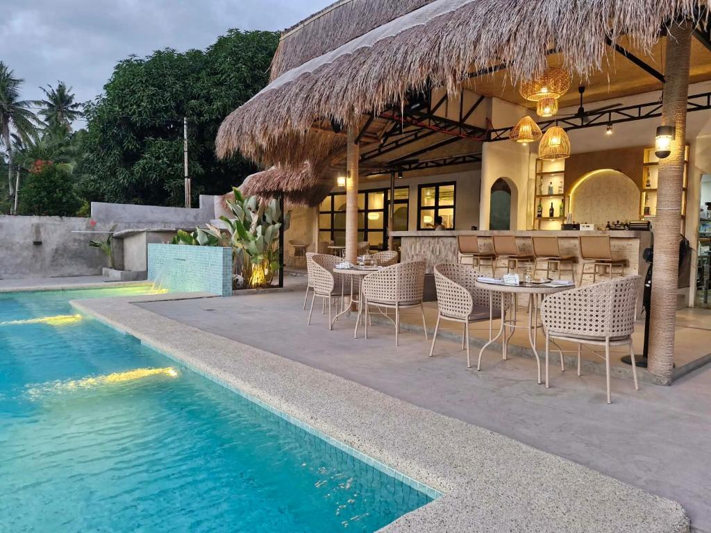a restaurant with tables and chairs next to a swimming pool at Villa Alessandra Homestay in Moalboal