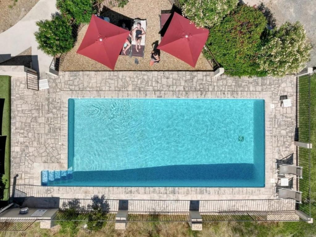 Draufsicht auf ein Schwimmbecken mit zwei roten Sonnenschirmen in der Unterkunft Vilajoun in Joucas