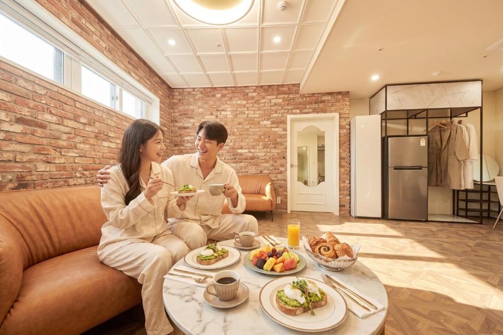 a man and woman sitting on a couch eating food at Restia Incheon Bay Hotel in Incheon