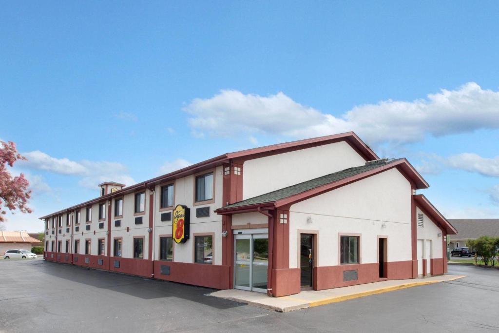 a large red and white building in a parking lot at Super 8 by Wyndham Crystal Lake in Crystal Lake