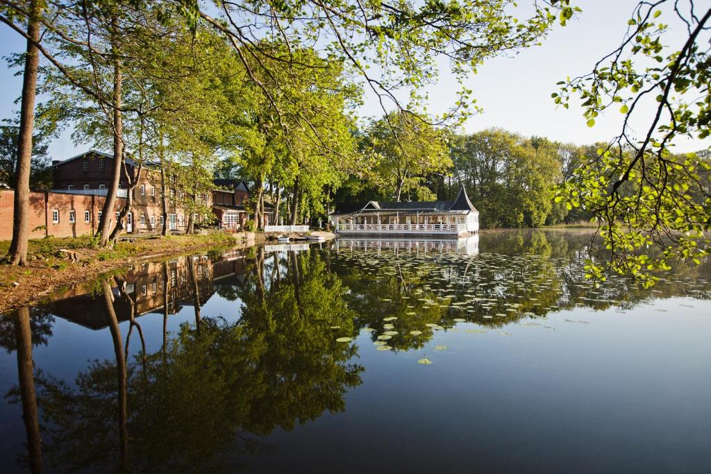 a house on a river with a building in the background at Bokel-Mühle am See in Bokel