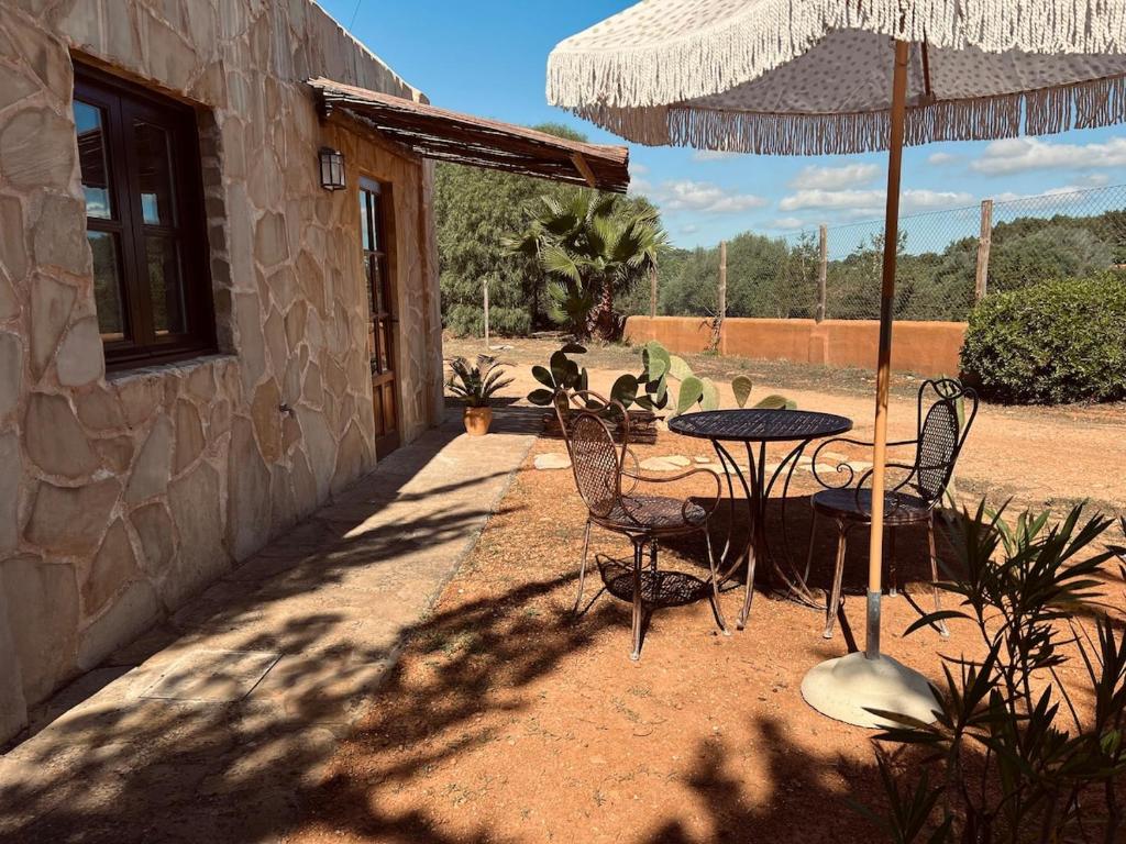 a patio with a table and chairs and an umbrella at Balearic Sunset Apartment in Santa Gertrudis de Fruitera