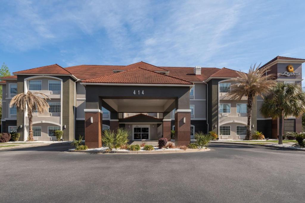 a hotel building with palm trees in front of it at La Quinta by Wyndham Savannah Airport - Pooler in Savannah