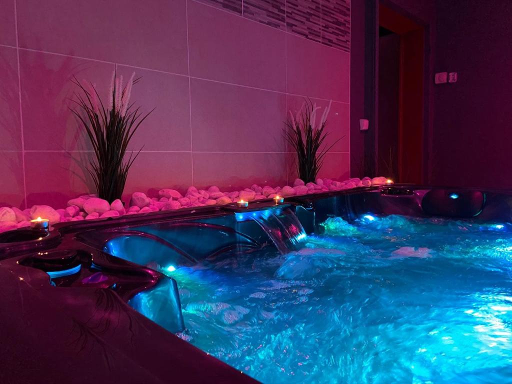a hot tub in a room with pink lighting at La Suite Privée - Maison Privative Spa & Sauna in Évreux