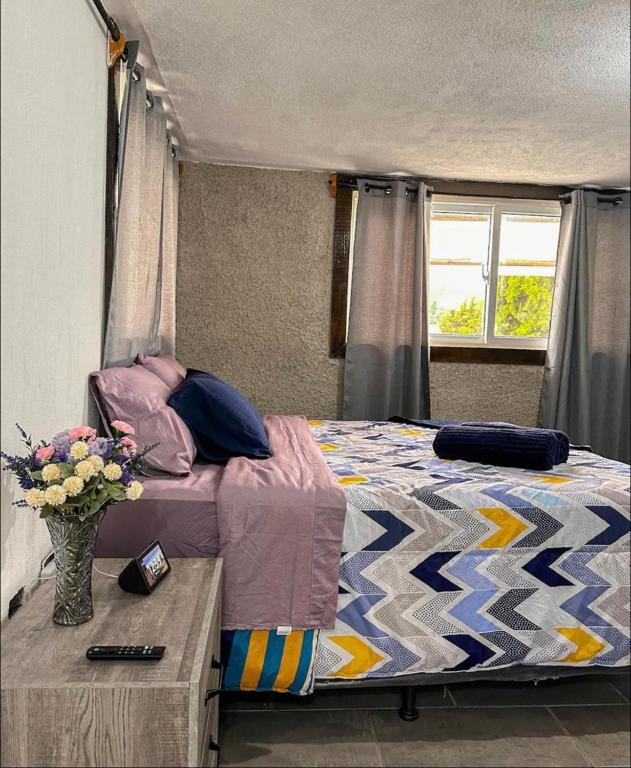 a bedroom with a bed and a vase of flowers on a table at Hospedajes Alta Terra in Quetzaltenango