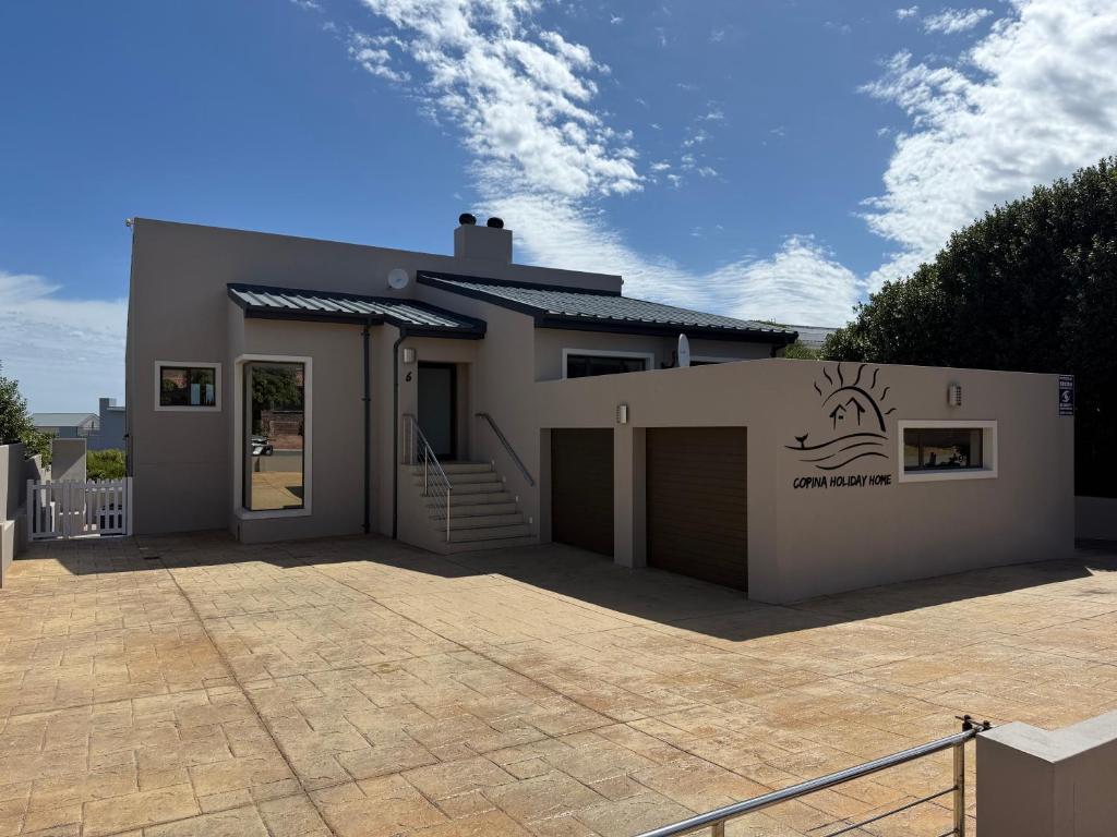 a house with a driveway and a garage at Copina Holiday Home in De Kelders