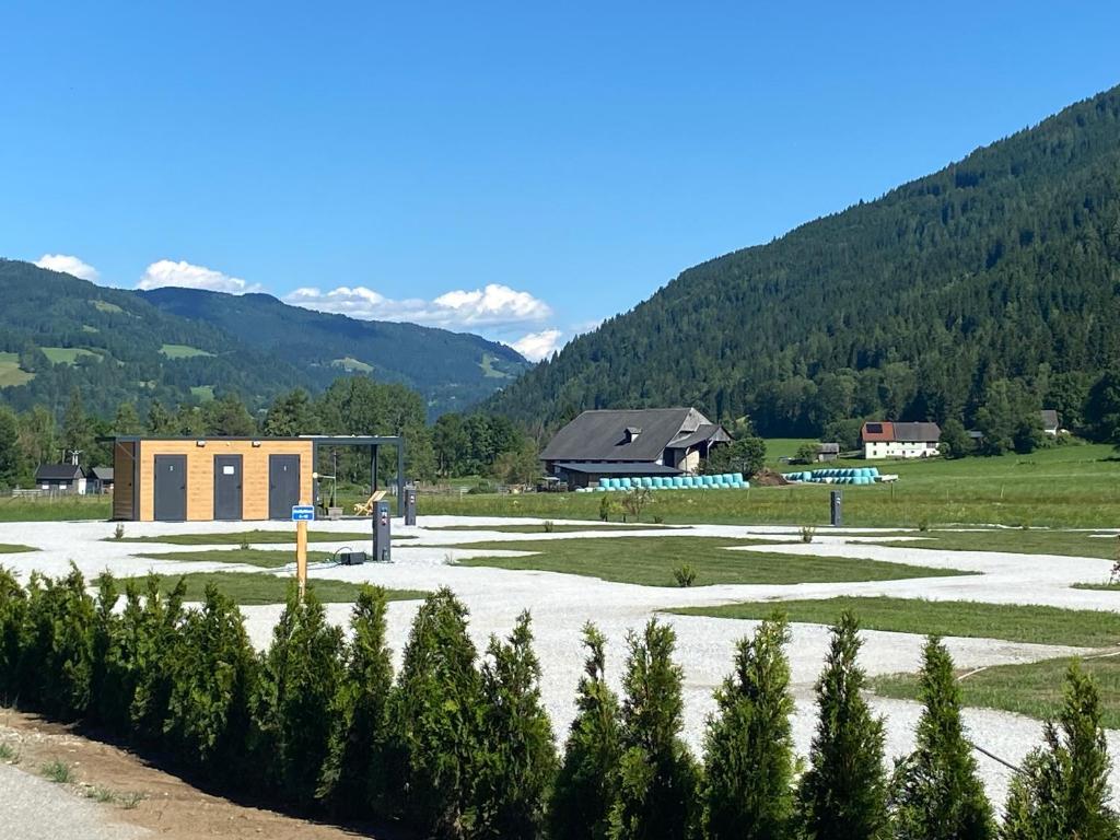 a building in a field with mountains in the background at Wiesn Relax Camping Steiner in Ranten