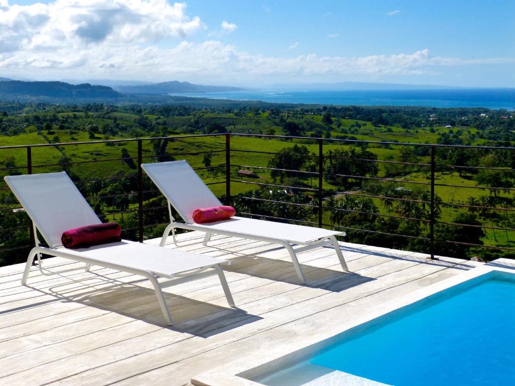 - deux chaises assises sur une terrasse à côté d'une piscine dans l'établissement Villa Vertigo-Vista Linda, à Río San Juan