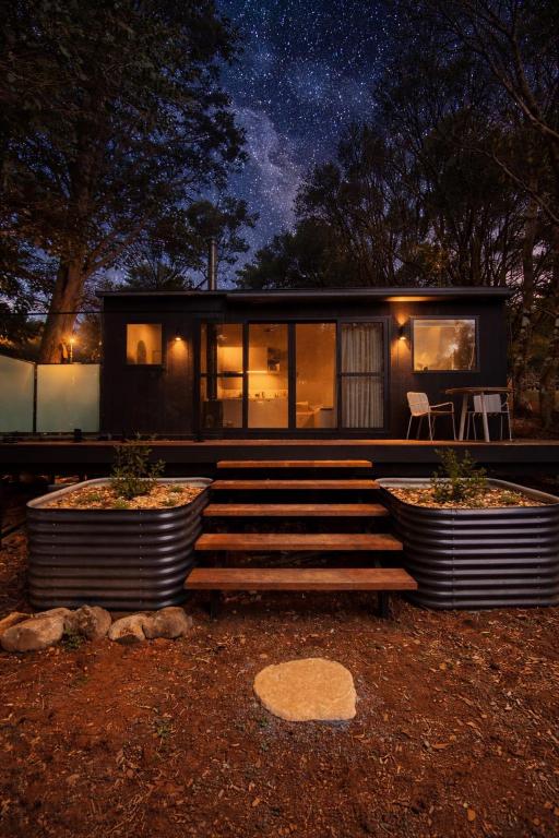 a small black house with two large pots in front of it at The Flower Sanctuary Tiny Home in Springbrook
