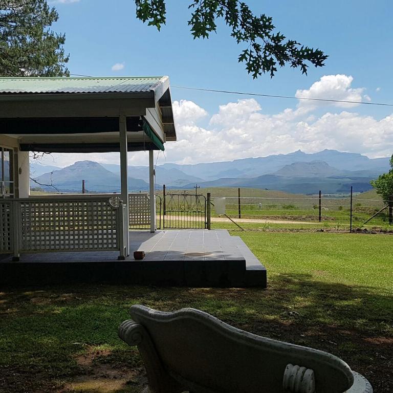 a bench in front of a building with mountains in the background at 37 Valley View Cottage in Underberg
